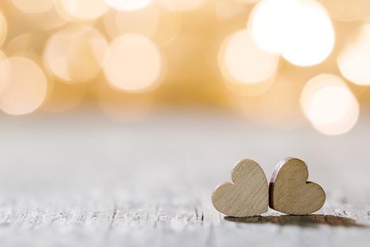 Two handmade wooden hearts on beautiful golden bokeh background. Vintage style. Love Valentine's Day concept.