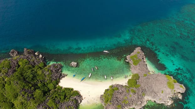Sandy beach with tourists and tropical island by atoll with coral reef, top view. Lahos Island, Caramoan Islands, Philippines. Summer and travel vacation concept.