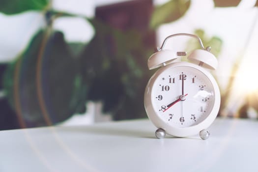 Selective focus of alarm clock show 8 o'clock or 8 a.m. on table with nature bokeh background. Time in life concept.