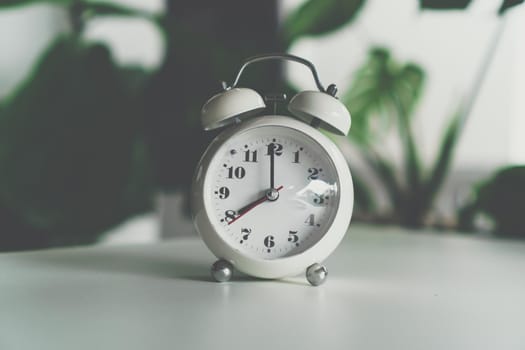 Selective focus of alarm clock show 8 o'clock or 8 a.m. on table with nature bokeh background. Time in life concept.