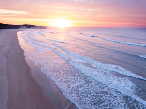 Aerial of sunrise over the ocean and empty beach