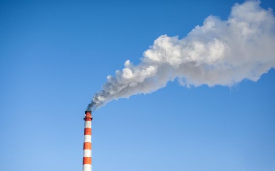 White thick smoke from the boiler room chimney. Smoke against the blue sky. Air pollution. Heating of the city. Industrial zone.