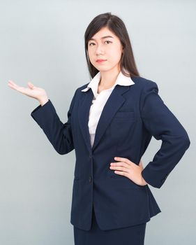 Asian woman in suit open hand palm gestures with empty space isolated on gray background