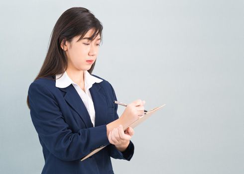 Portrait of Asian woman long hair and wearing suit  with clipboard and pen in hands thinking about success, isolated on white background