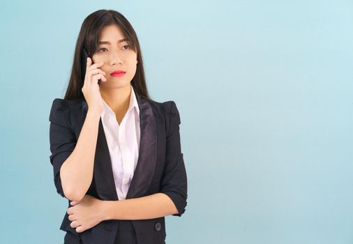 Young Asian women in suit standing posing using her phone against blue background