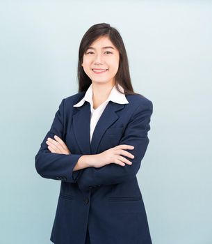 Teenage girl long hair is standing with her arms crossed wearing suit and white shirt on blue background