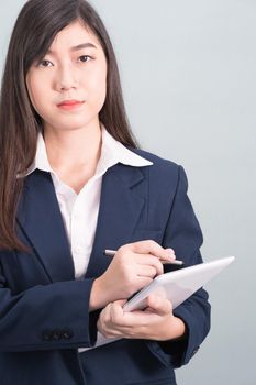 Woman in suit using computer digital tablet isolated on gray background