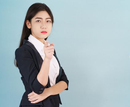 Asian woman looking at camera and pointing finger on blue background