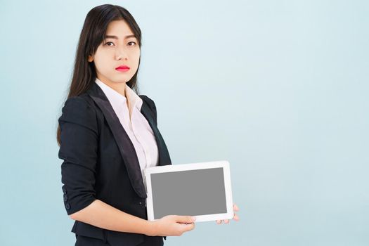 Young women in suit holding her digital tablet standing against blue background