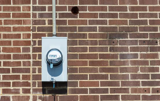 Horizontal shot of a commercial electric meter on an old red brick wall with copy space.