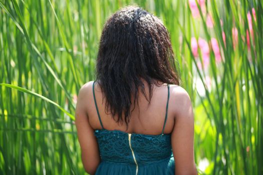 Cheerful young woman standing among tropical leaf.