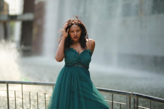 Cheerful young woman standing outdoor against water park in the garden.