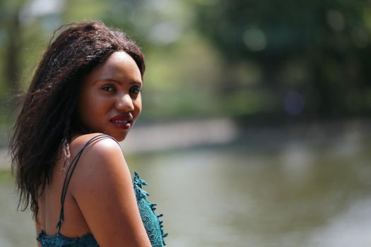 Cheerful young woman standing outdoor against water park in the garden.