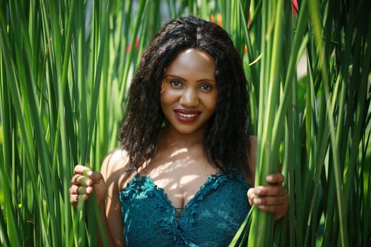 Cheerful young woman standing among tropical leaf.