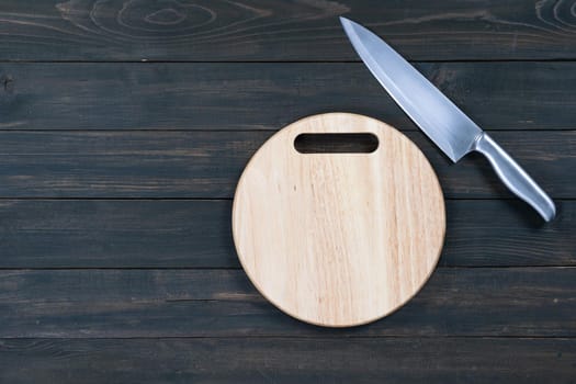 kitchen knife and wooden round empty cutting board on a wooden table close up