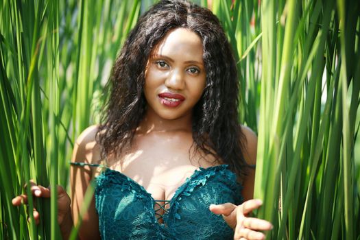 Cheerful young woman standing among tropical leaf.
