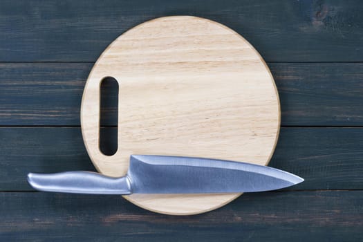 Close up kitchen knife and round cutting board on a wooden table