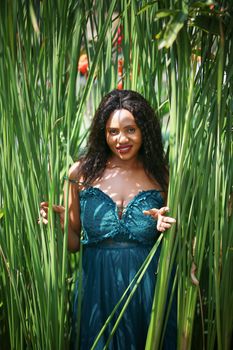 Cheerful young woman standing among tropical leaf.