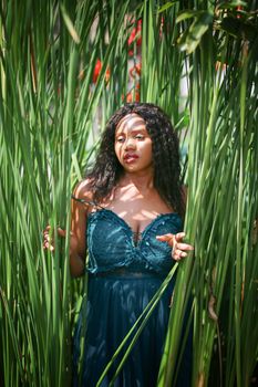 Cheerful young woman standing among tropical leaf.