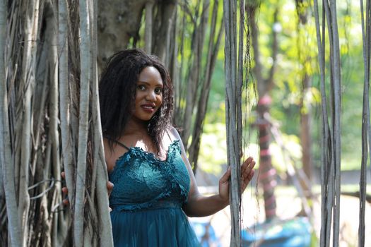 Cheerful young woman standing by tree in the jungle. 
