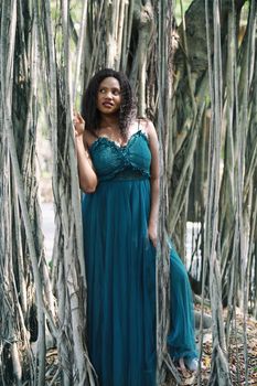 Cheerful young woman standing by tree in the jungle. 