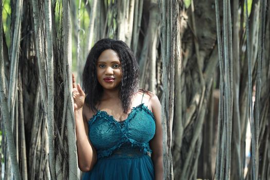 Cheerful young woman standing by tree in the jungle. 