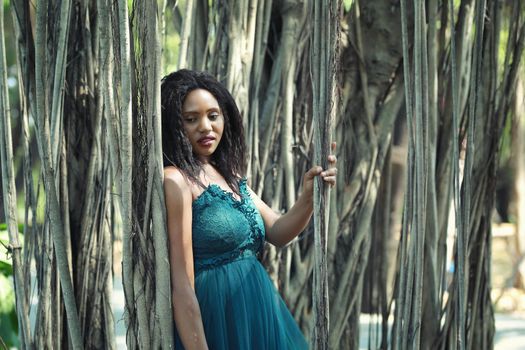 Cheerful young woman standing by tree in the jungle. 