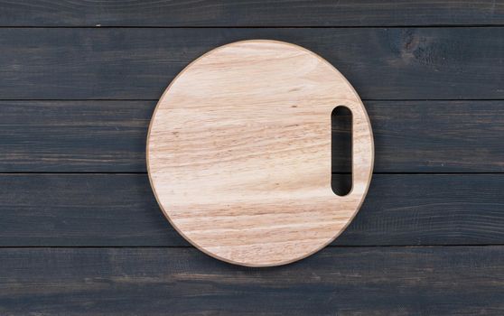 Wooden round empty cutting board on a wooden table close up