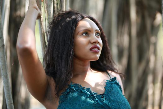 Cheerful young woman standing by tree in the jungle. 