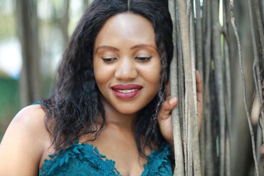 Cheerful young woman standing by tree in the jungle. 