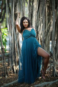 Cheerful young woman standing by tree in the jungle. 