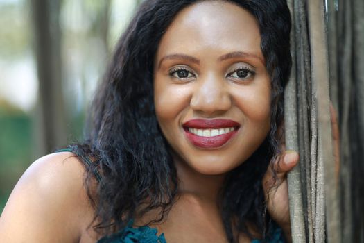 Cheerful young woman standing by tree in the jungle. 