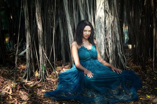 Cheerful young woman standing by tree in the jungle. 