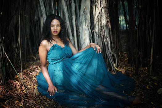 Cheerful young woman standing by tree in the jungle. 