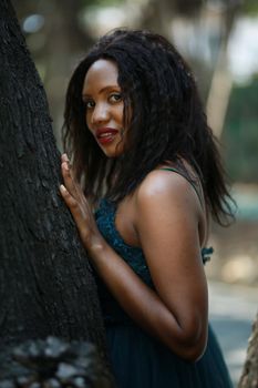 Cheerful young woman standing by tree in the jungle. 