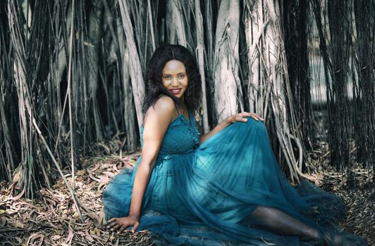 Cheerful young woman standing by tree in the jungle. 