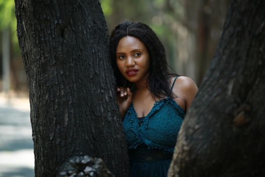 Cheerful young woman standing by tree in the jungle. 