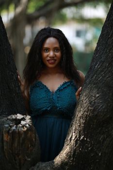 Cheerful young woman standing by tree in the jungle. 