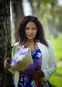 Cheerful young woman standing at outdoor with flower.