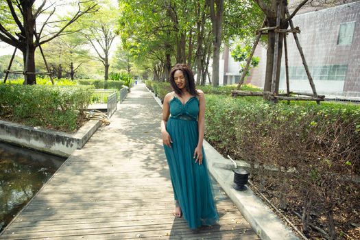 Cheerful young woman standing among tropical garden.