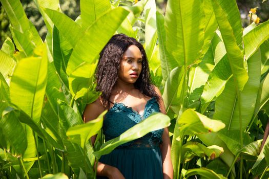 Cheerful young woman standing among tropical garden.