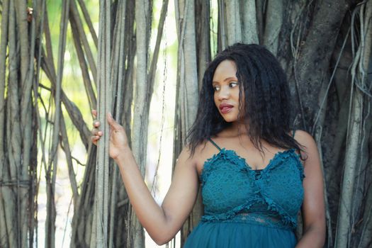 Cheerful young woman standing among tropical garden.