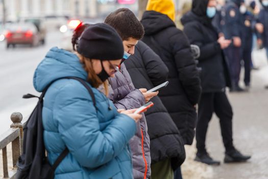 Tula, Russia - January 23, 2021: Teenagers using mobile phones while waiting of public mass meeting in support of Navalny to start.
