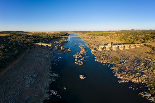 Destroyed abandoned Ajuda bridge drone aerial view, crossing the Guadiana river between Spain and Portugal