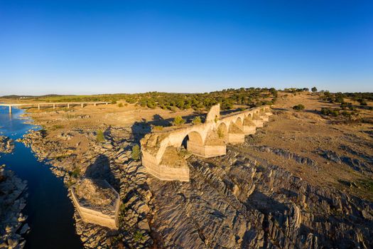 Destroyed abandoned Ajuda bridge drone aerial view, crossing the Guadiana river between Spain and Portugal