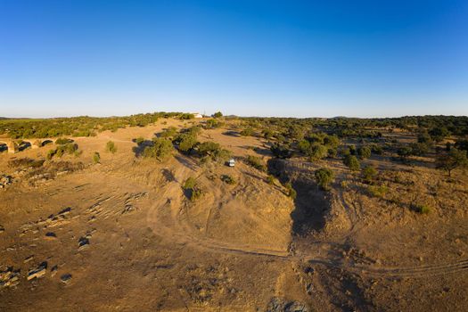 Camper van drone aerial view alone on an Alentejo landscape between the trees, in Portugal