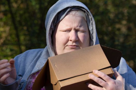 Woman in a grey hoodie holding a closed cardboard box