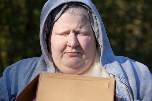 Woman in a grey hoodie holding a closed cardboard box