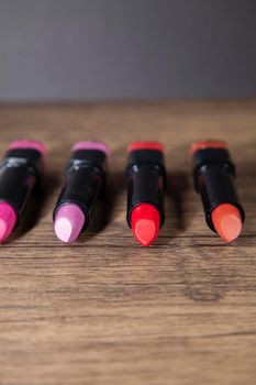 Four shades of pink and red lipstick on a wooden counter