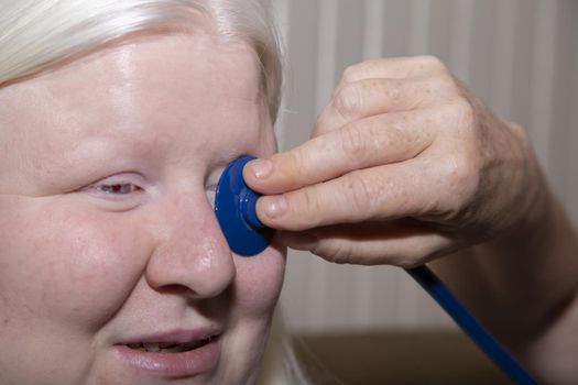 Medical professional holding a stethoscope up to a patient's eye
